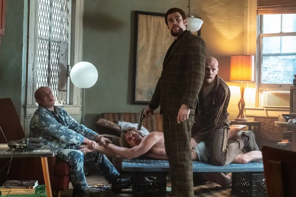 Pavel (Nikita Kukushkin, left), Colorado (Bad Bunny, standing), and Aleksei (Yuri Kolokolnikov, right) apply some pressure to Hank (Austin Butler, 2nd from left) in Columbia Pictures CAUGHT STEALING. photo by: Niko Tavernise \\u00A9 2025 CTMG, Inc. All Rights Reserved.