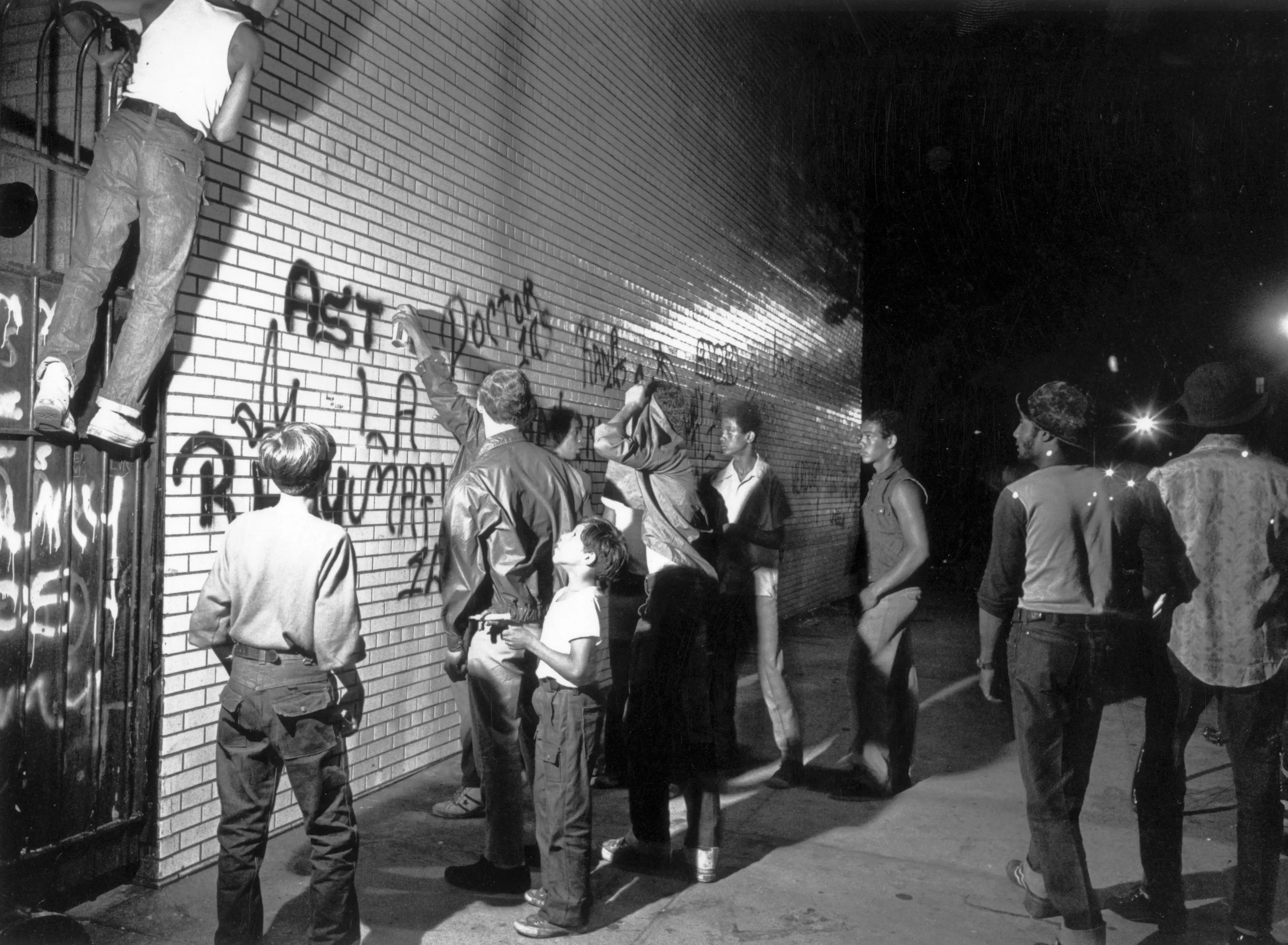 July 1972:  A group of youths spraypaint graffiti on a New York wall.  (Photo by F. Roy Kemp/BIPs/Getty Images)