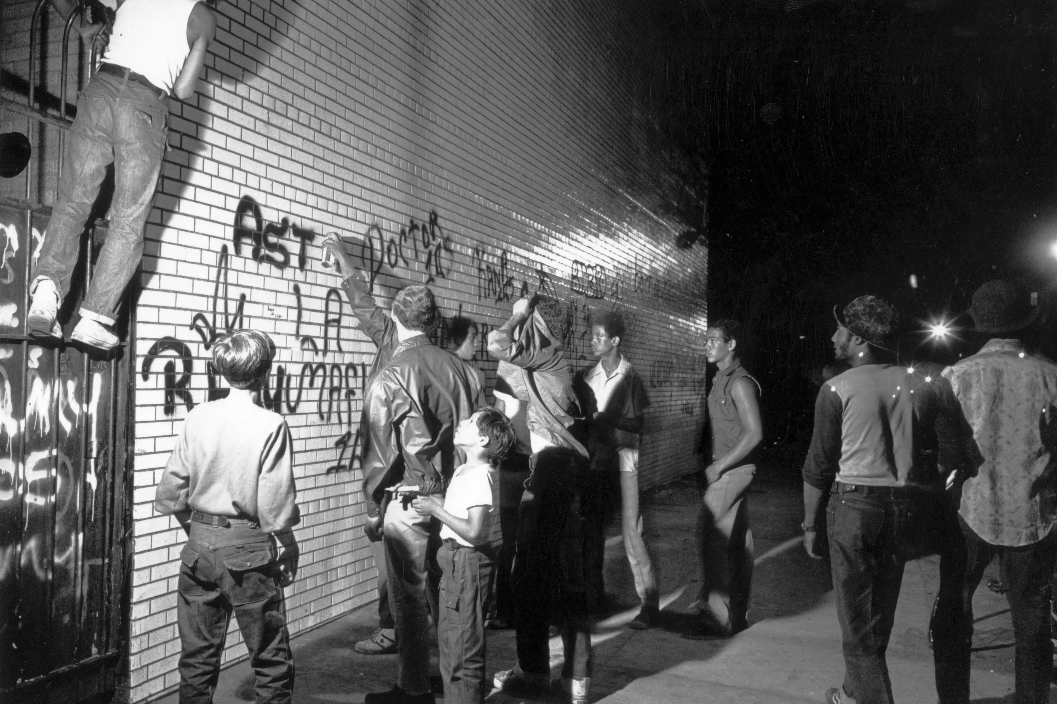 July 1972:  A group of youths spraypaint graffiti on a New York wall.  (Photo by F. Roy Kemp/BIPs/Getty Images)